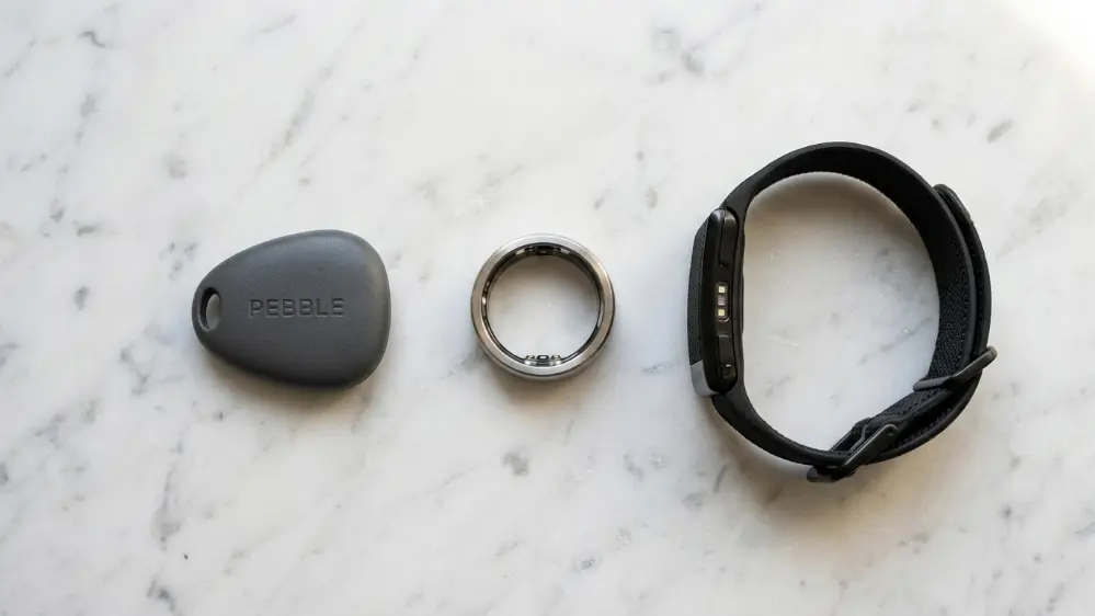Flat lay comparison of Fitbit Air Oura Ring and Whoop wearables