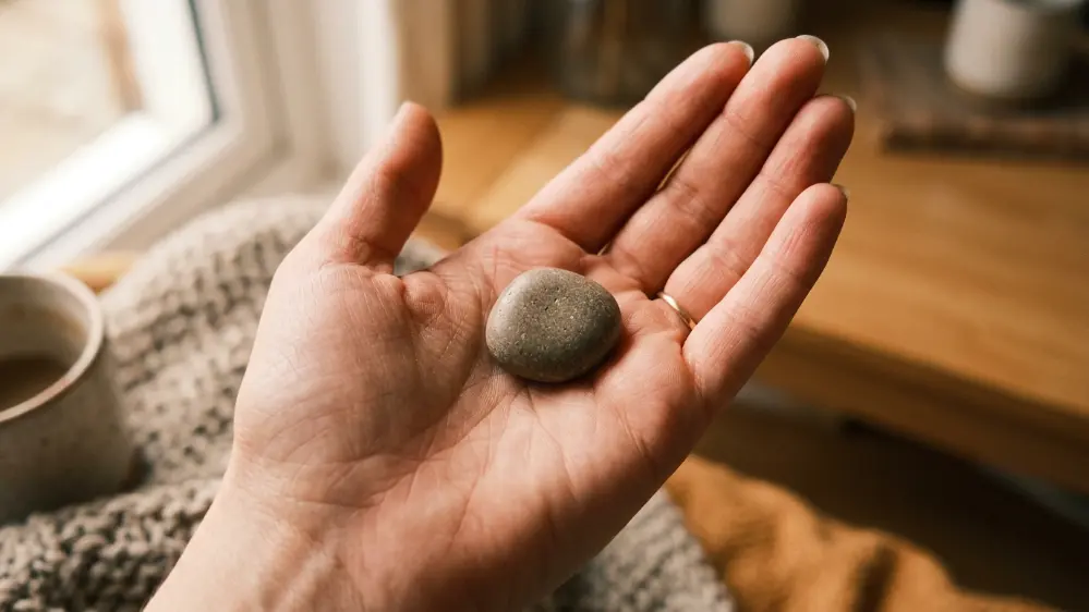 What Is OpenAI's New AI Device (the Jony Ive Project)? Everything We Know So Far 4 Hand holding a smooth pocket sized AI device prototype
